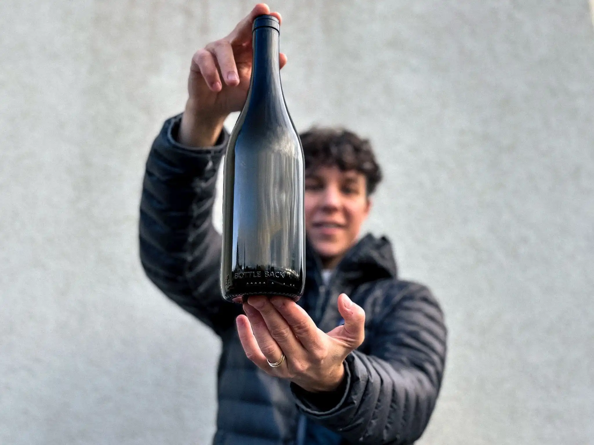 four bottles of wine are hanging on a stone wall